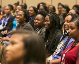 Black women smile in the audience during a GHC 17 session