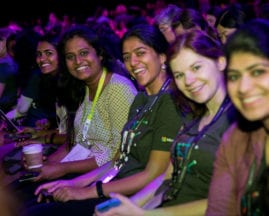Audience members smile at the camera during the GHC 17 Wednesday Keynote