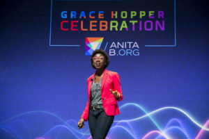 Joy Buolamwini stands on stage during her GHC 18 Featured Session on AI