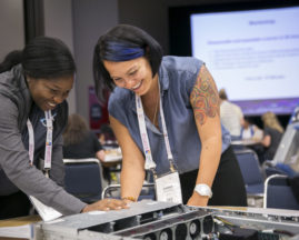 A Black woman and Caucasian woman work together on a project at the GHC 18 Open Source Day