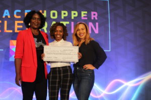 Shakeia Kegler, winner of the 2018 AnitaB.org PitcHER contest, holds her check on stage with moderator Mandela SH Dixon