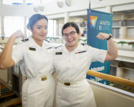 Two women attendees flex their muscles in their U.S. Naval Academy uniforms at GHC 19