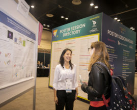 A poster presenter talks about her research to another young woman at GHC 19